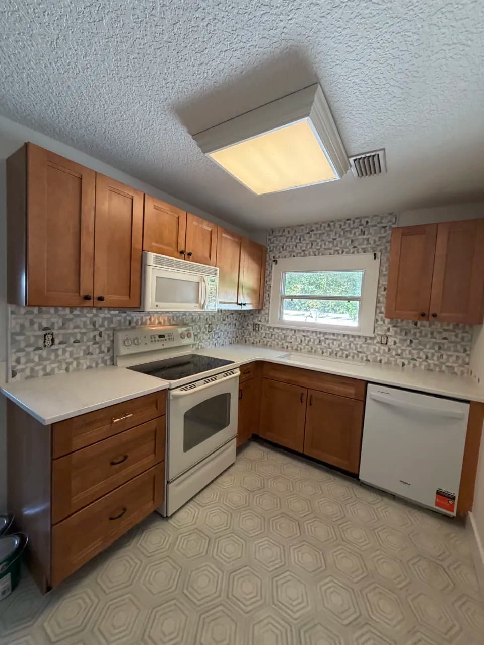 Marble mosaic kitchen backsplash above counters and porcelain hex flooring below