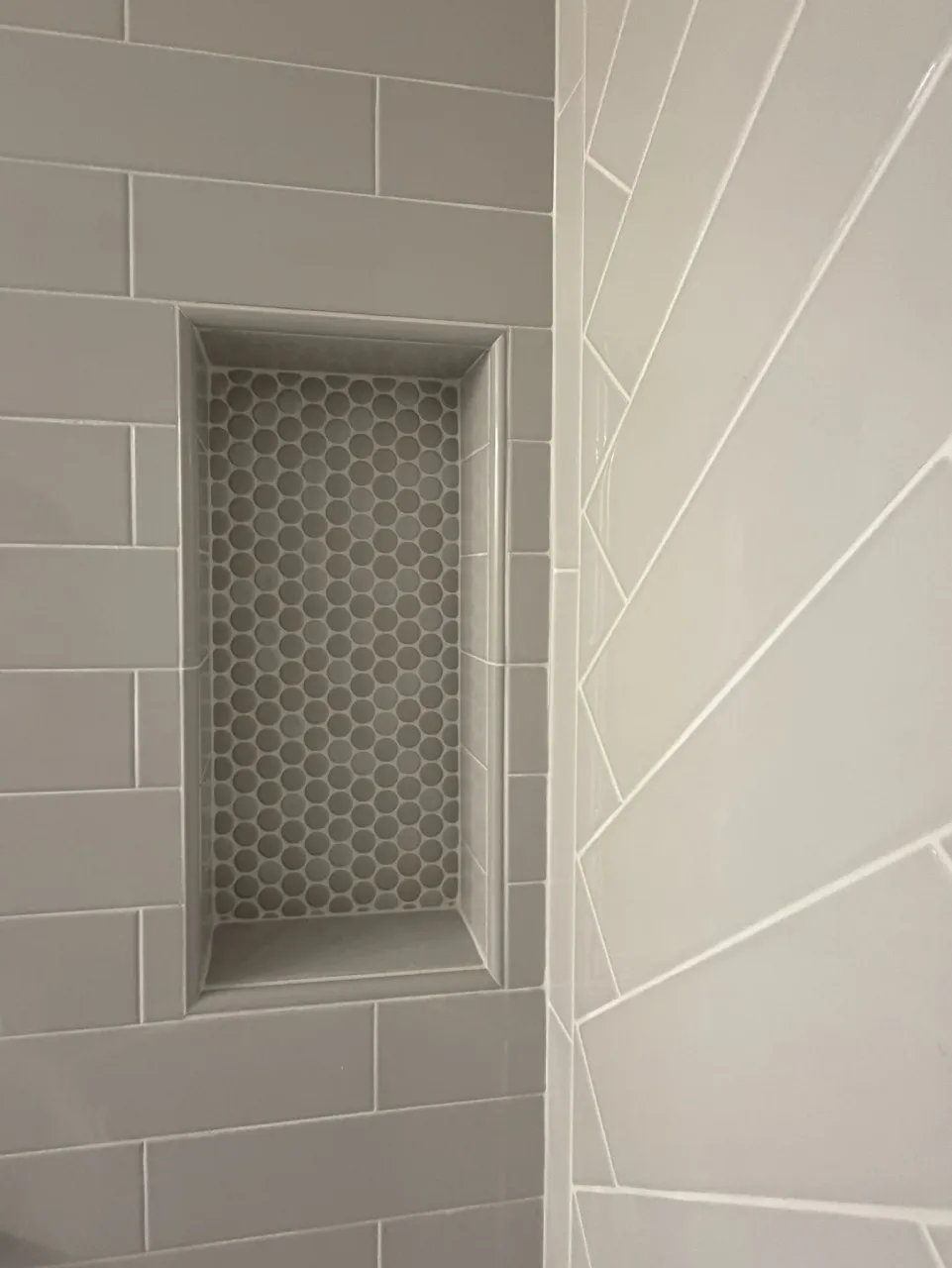 Recessed shower niche with mosaic backing and ceramic surround