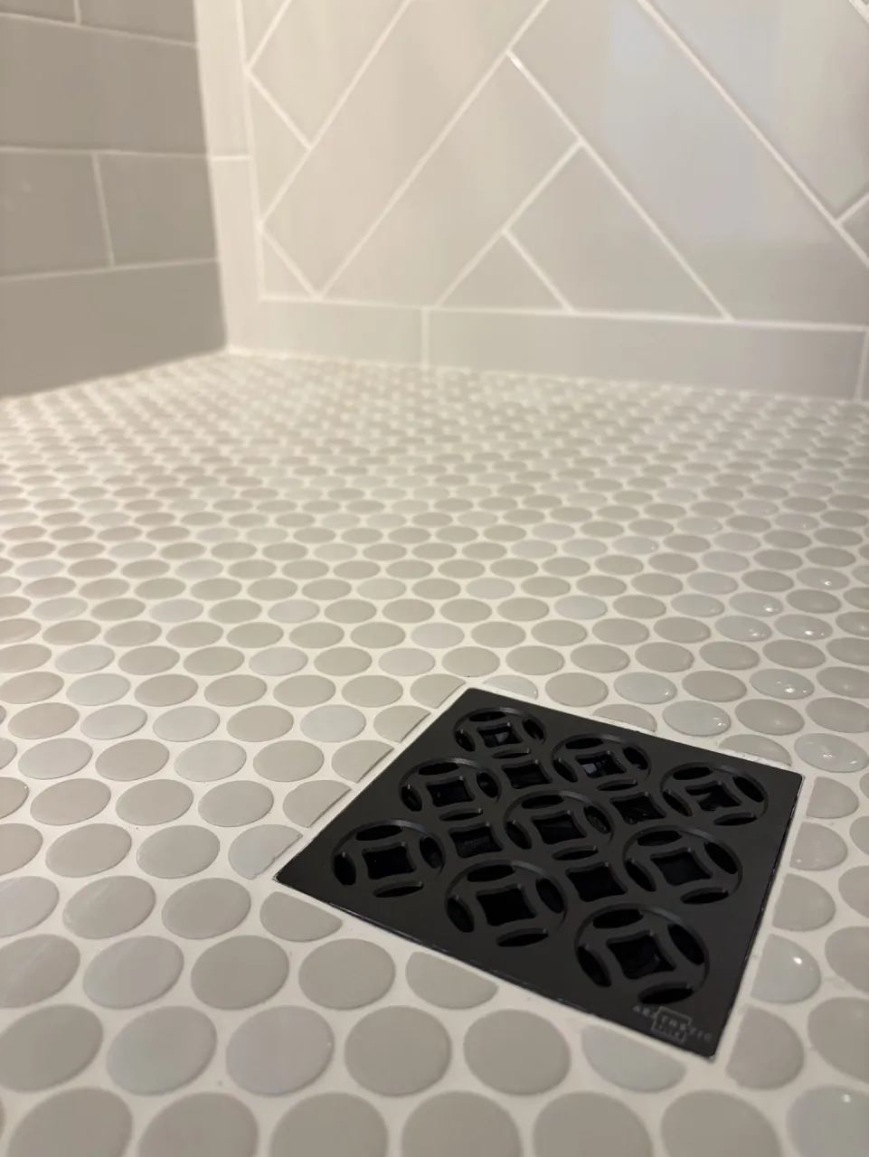 Decorative dark drain grate within the shower mosaic floor