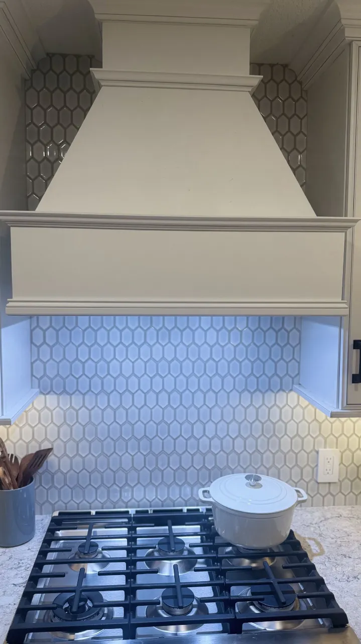 Detailed mosaic tile cuts along the range hood