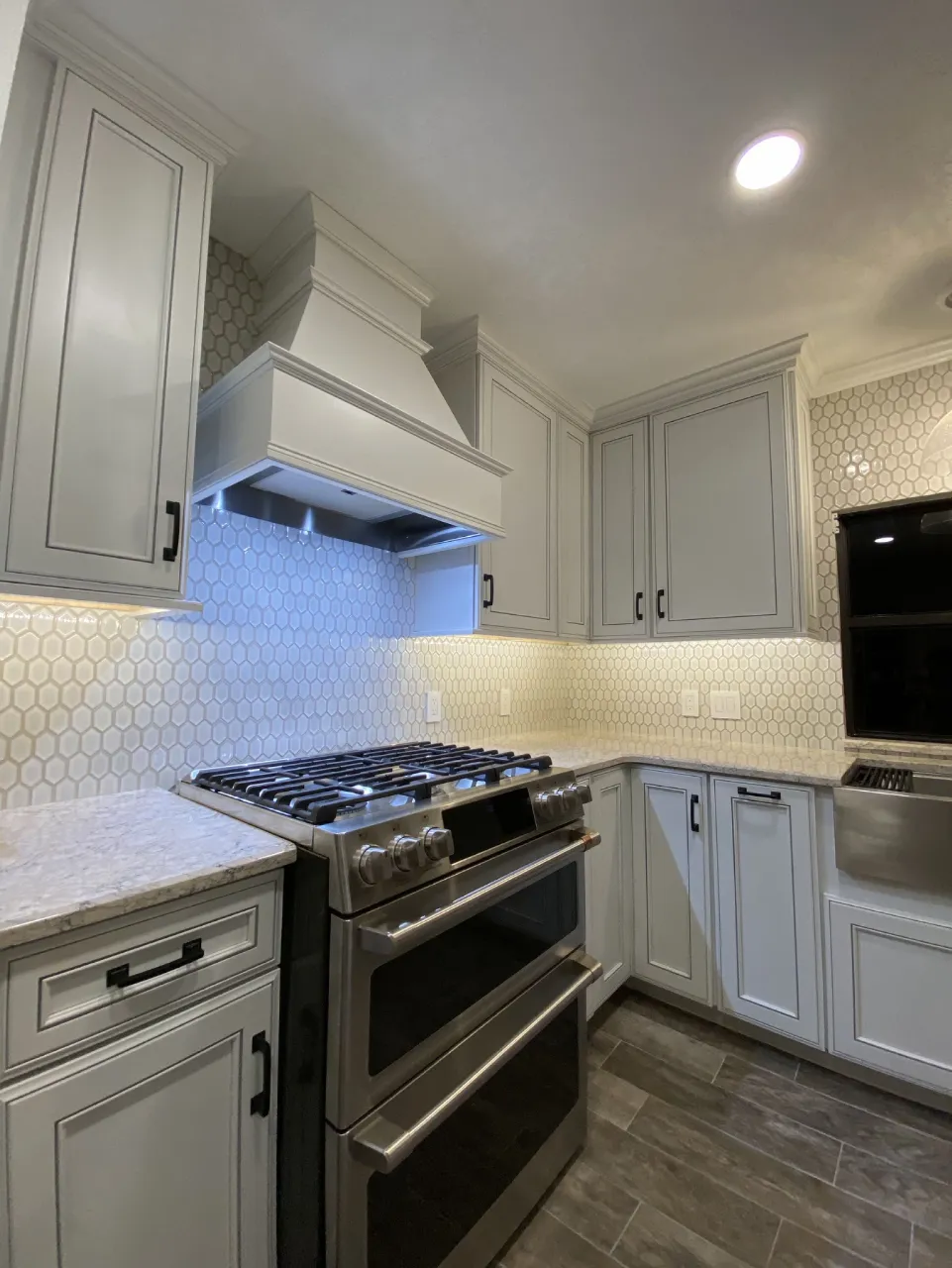 Patterned kitchen backsplash around the range beneath gray cabinets