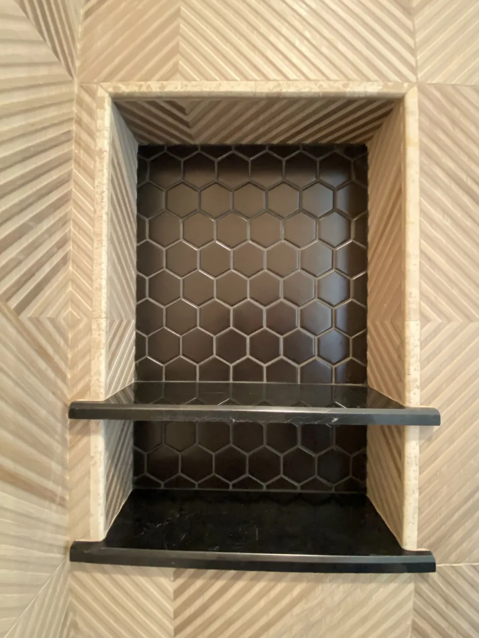 Framed shower niche with hex mosaic backing and dark shelves