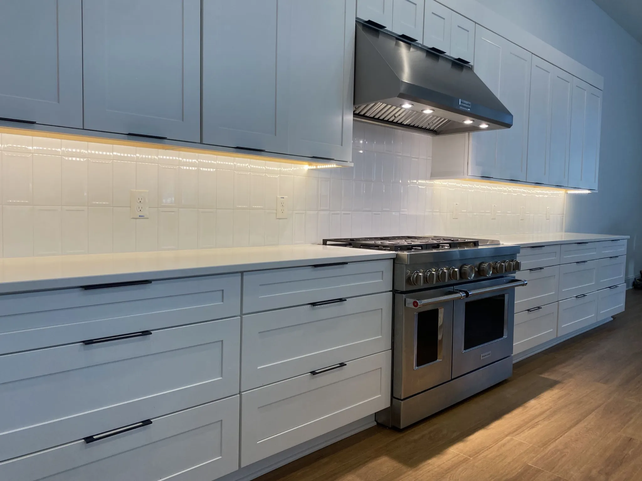 White ceramic backsplash behind a range beneath cabinetry
