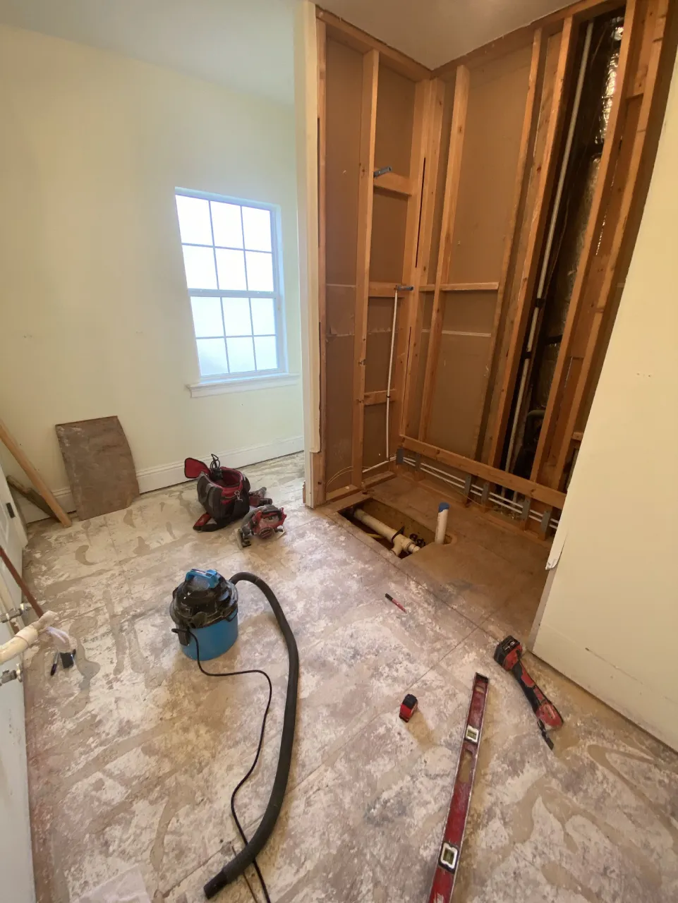 Opened wall framing and exposed floor during the bathtub conversion