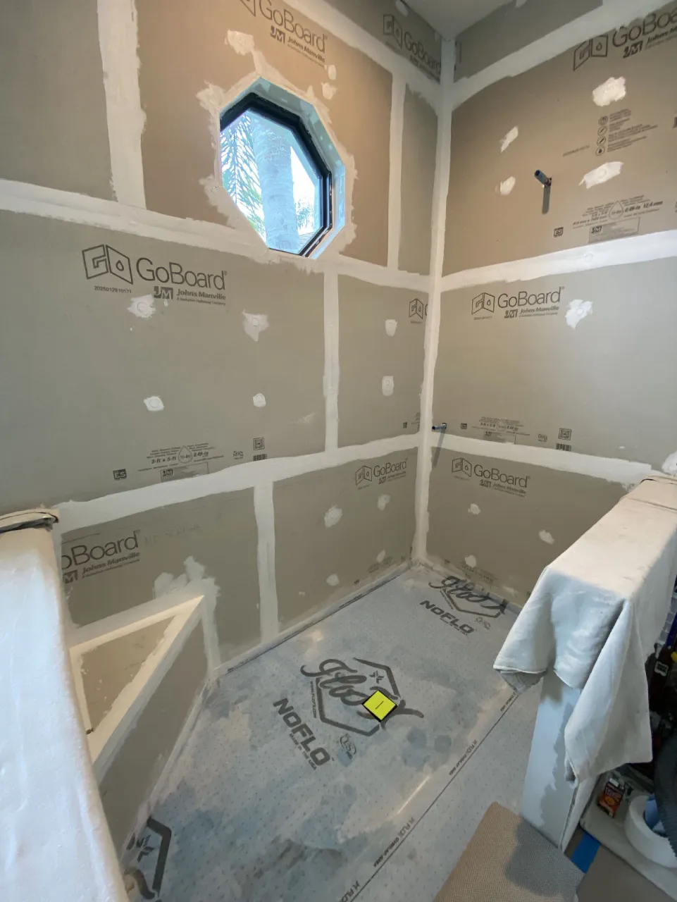 Prepared shower walls and base before tile, with surrounding surfaces protected