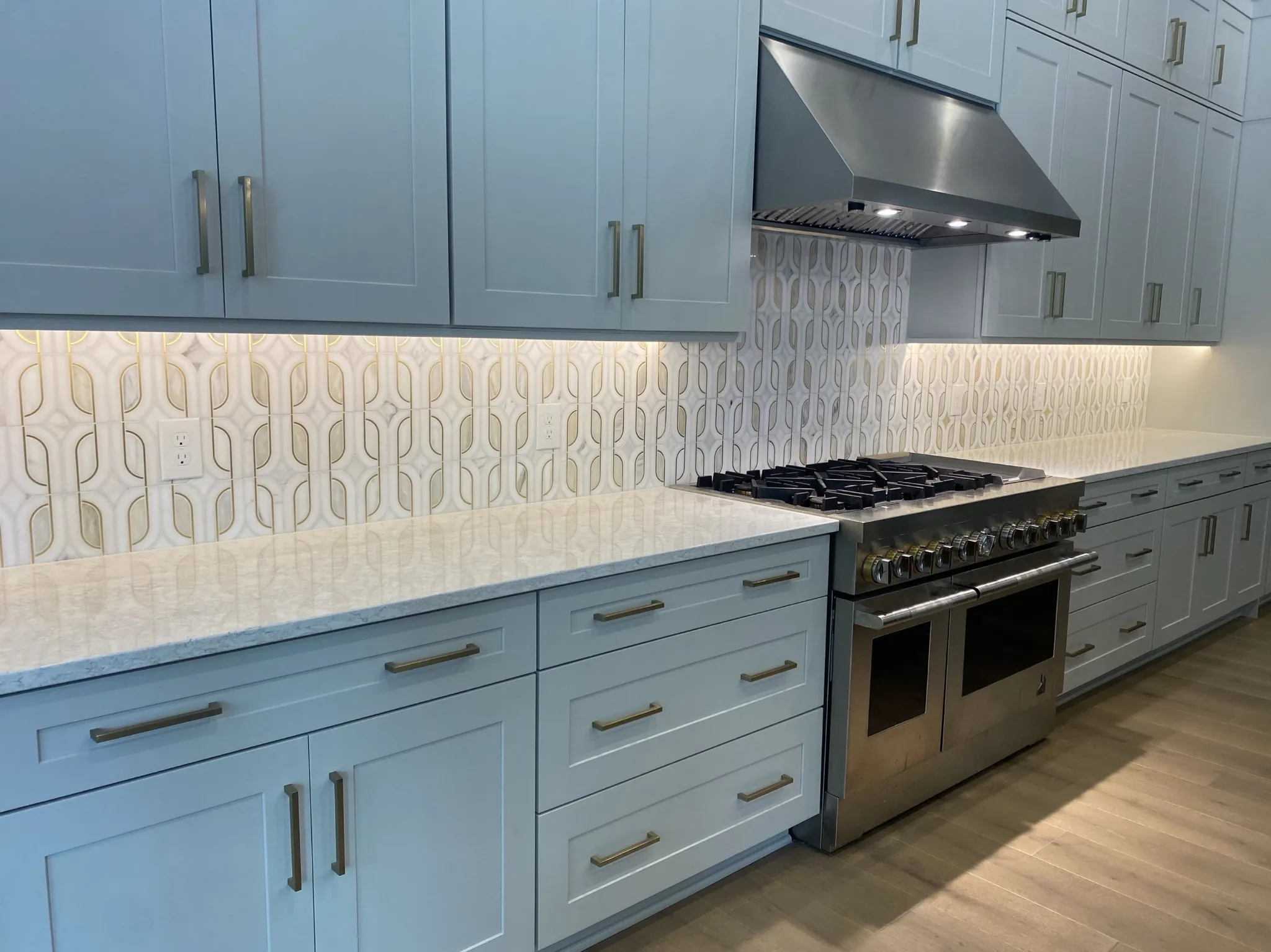 Marble mosaic kitchen backsplash beneath blue cabinets