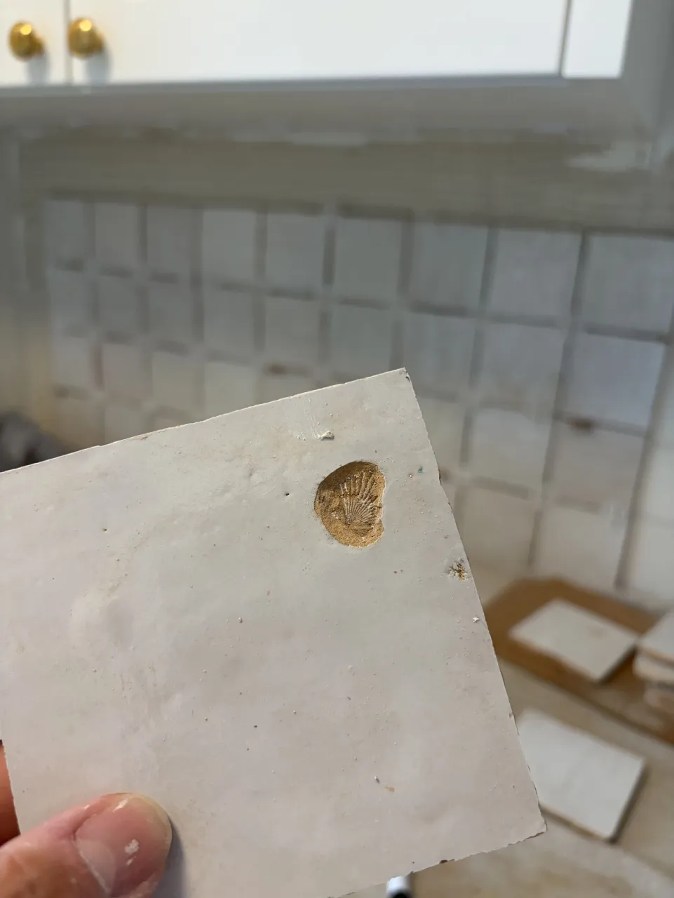 Back of an individual handmade tile held up during preparation
