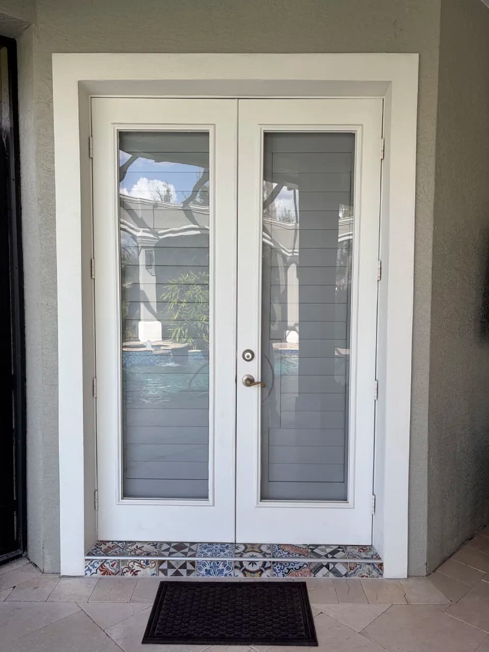 Patterned porcelain step beneath a pair of exterior doors