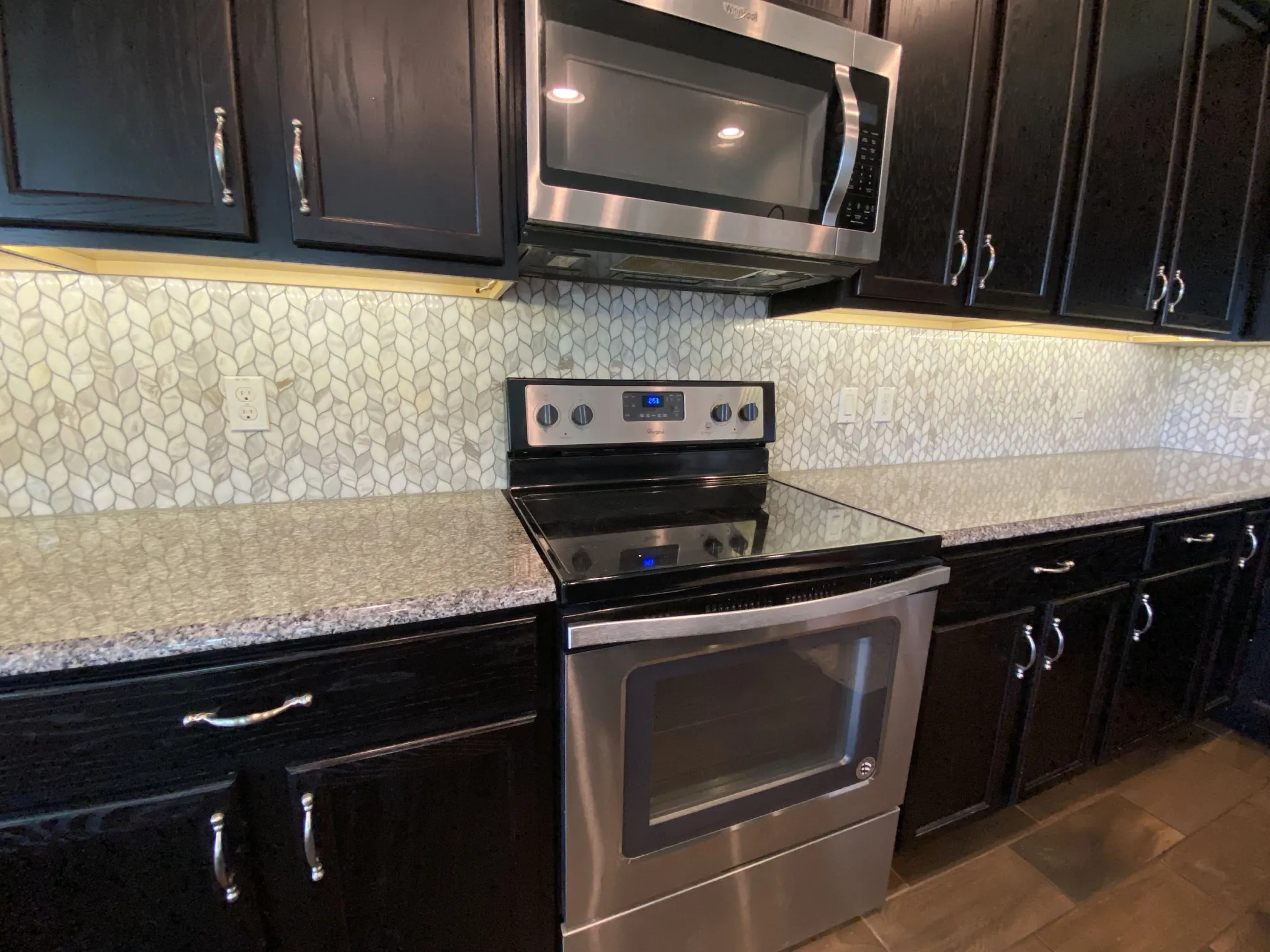 Completed marble leaf backsplash behind the range and below dark cabinets